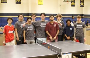 A team of teenagers standing behind a ping pong table